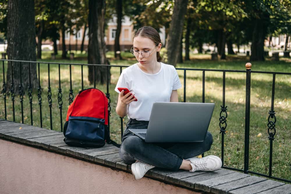 Online jobs for college students. Young woman student girl searching job with laptop outdoors in summer day. Side hustle for students